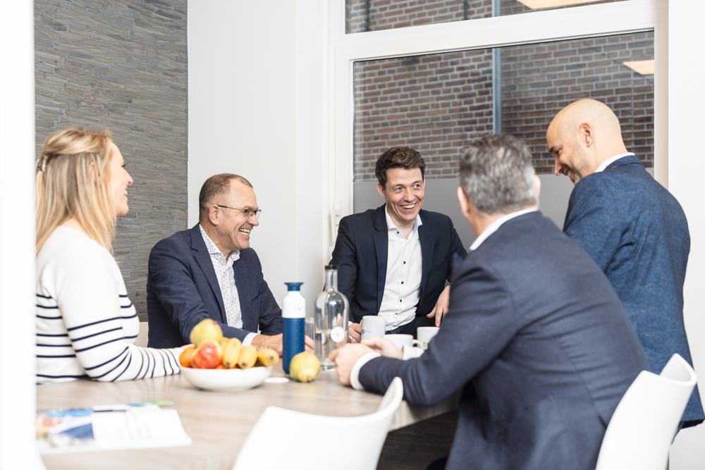 Collega's overleggen lachend rond een tafel